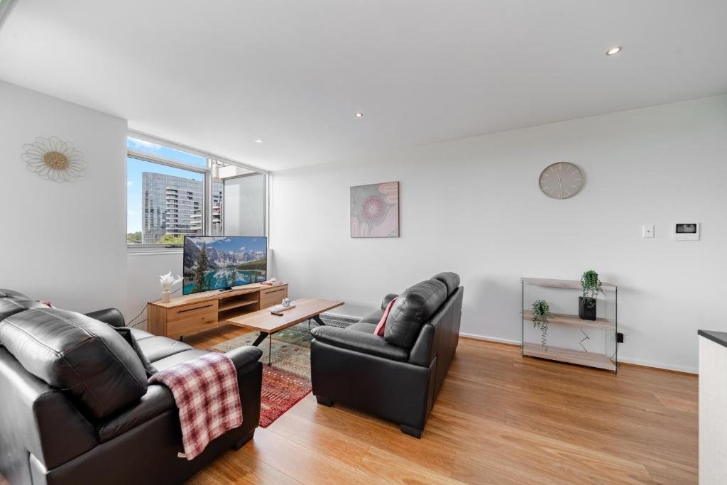 キャンベラにあるStylish 1-Bed Flat with Pool BBQ & Sauna Accessのソファ2つとテレビのあるリビングルーム