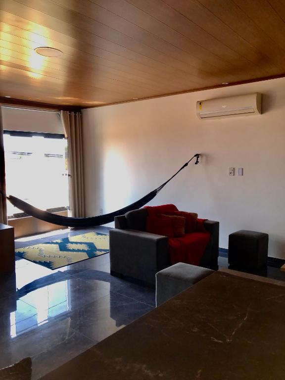 un soggiorno con un divano e un'amaca di Aconchego a Maceió