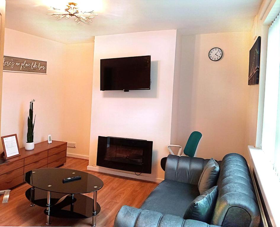 a living room with a leather couch and a fireplace at YPCC Hardaker Street in Bradford