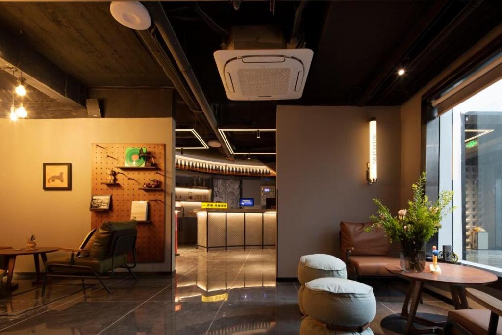 西安Mcsrh麦嘉·拾趣酒店(西安钟鼓楼回民街店)的大堂配有桌子、椅子和桌子。