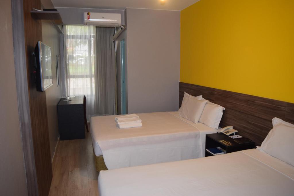 a hotel room with two beds and a yellow wall at Bittar Inn in Brasilia