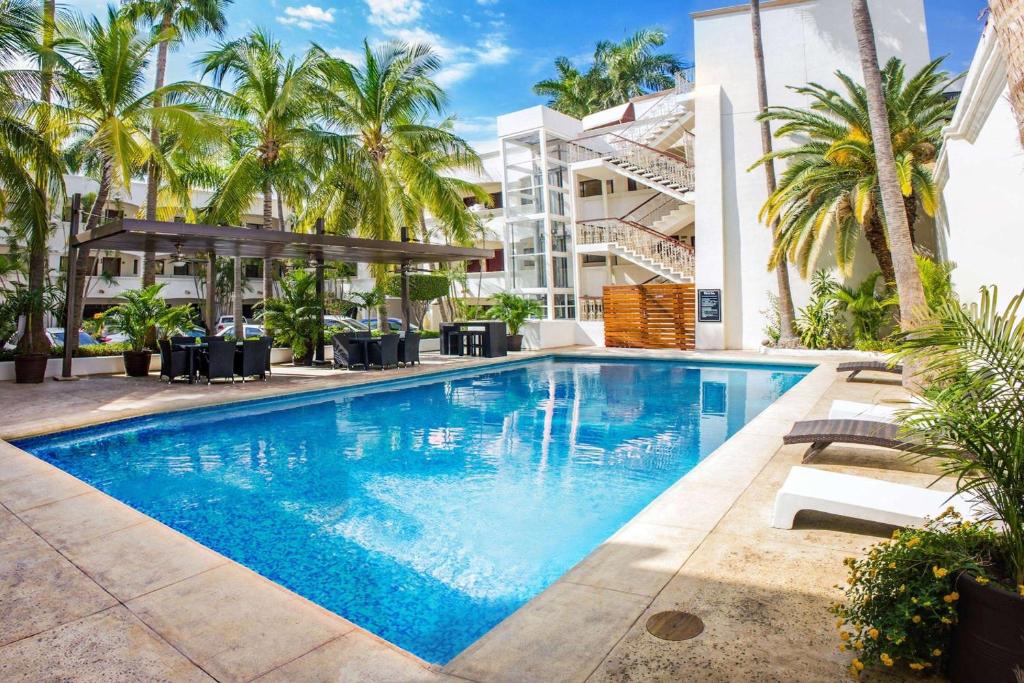 a swimming pool in front of a building with palm trees at Wyndham Garden Los Mochis Plaza Inn in Los Mochis