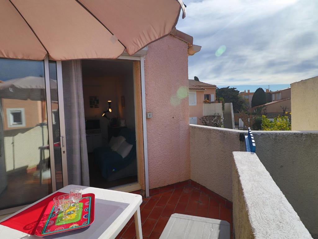 un balcon avec une table et un parasol dans l'établissement Charmant 2 pièces avec parking, proche plage - FR-1-472-206, à Sète