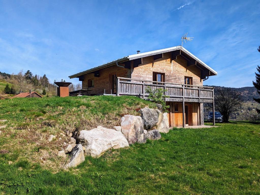 une grande maison en bois sur une colline avec des rochers dans l'établissement Chalet rénové calme avec terrasse et cheminée à Ventron - FR-1-589-783, à Ventron