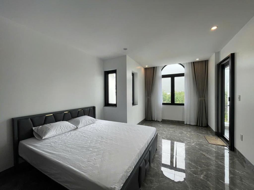 a bedroom with a large bed with white sheets and windows at Moc homestay- Near Bai Dai Beach in Cam Lâm