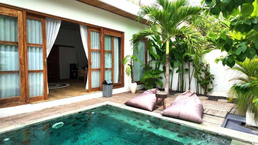 une piscine devant une maison avec des palmiers dans l'établissement ANANA PRIVATE VILLA nusa penida, à Nusa Penida