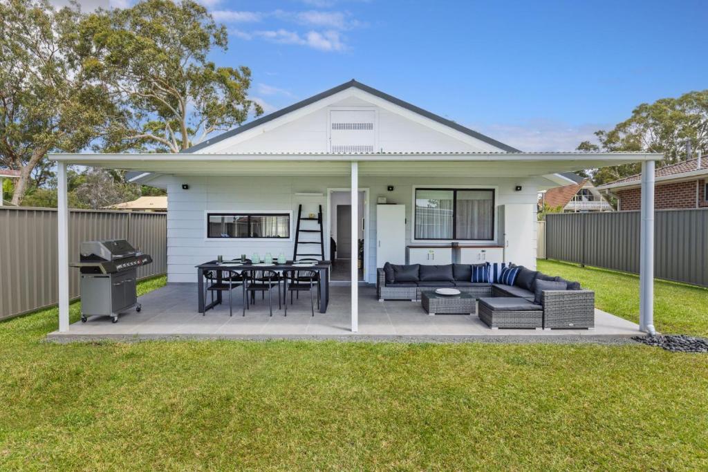 a white house with a patio and a grill at Serendipity Stays Jervis Bay - 5 Mins Walk to Beach in Sanctuary Point