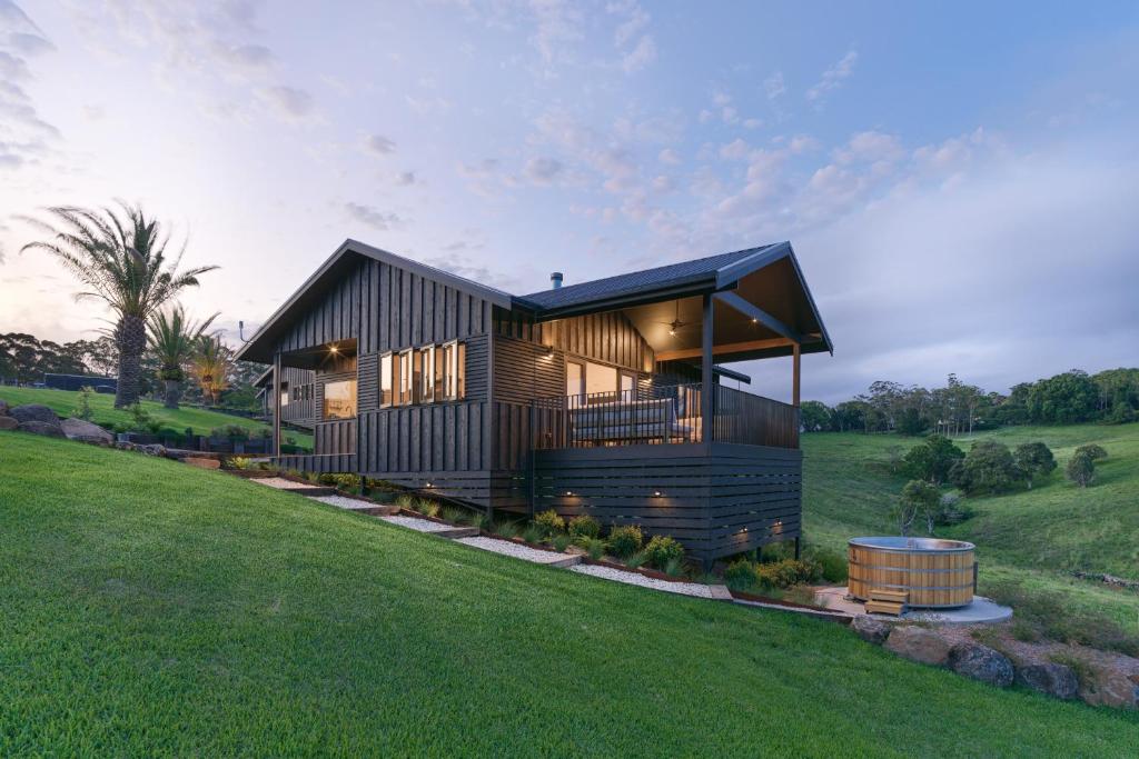 a modern house on a hill with a green field at Black Cockatoo Coorabell in Coorabell Creek