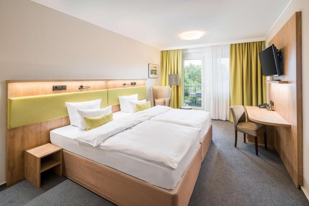 ライプツィヒにあるBest Western Hotel Windorfの大きなベッドと机があるホテルの部屋