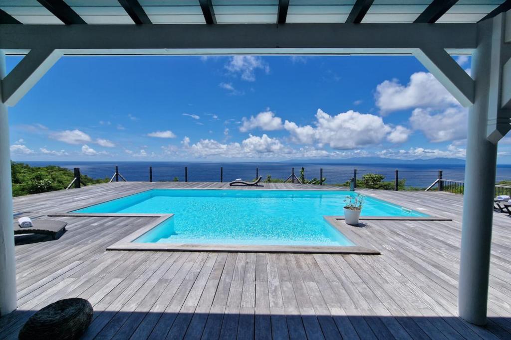 una piscina en una terraza con el océano en el fondo en Villa Horizon, en Grand-Bourg