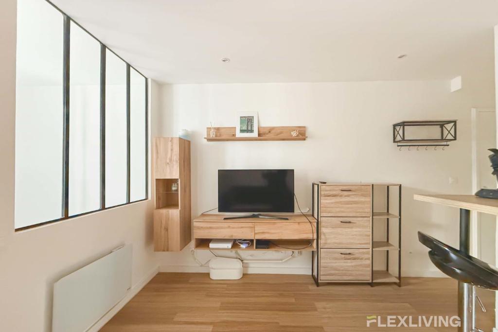 - un salon avec une télévision et un bureau avec une télévision dans l'établissement Flexliving - T2 - Montreuil, à Paris