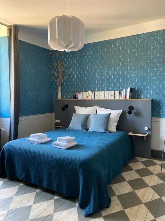 une chambre avec un lit bleu avec deux serviettes dessus dans l'établissement Le Presbytère de Darcey, à Darcey