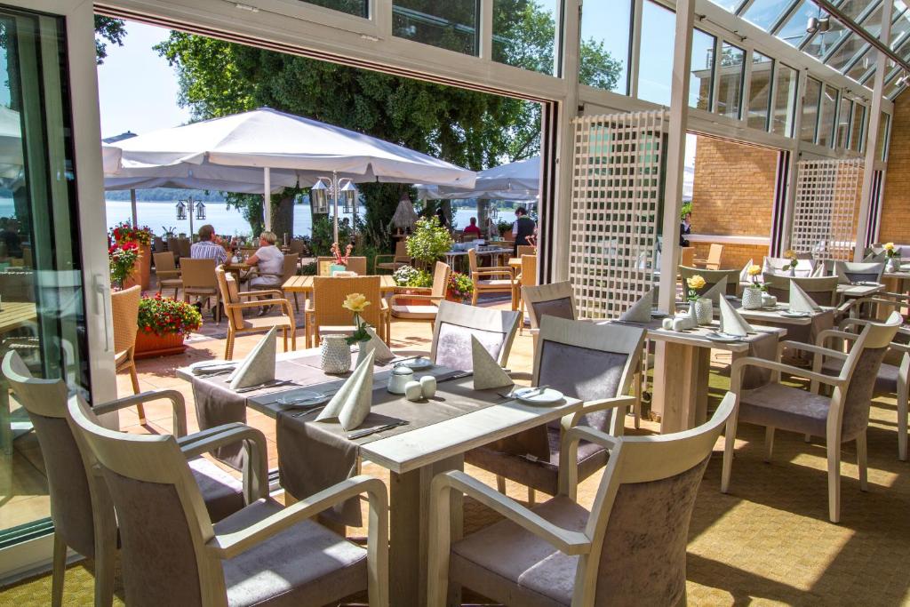 a restaurant with tables and chairs and people in the background at Falk Seehotel Plau am See in Plau am See