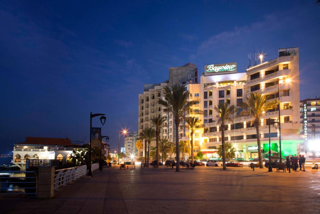 ベイルートにあるベイビュー ホテル ベイルートの夜の街のヤシの木が茂る大きな建物