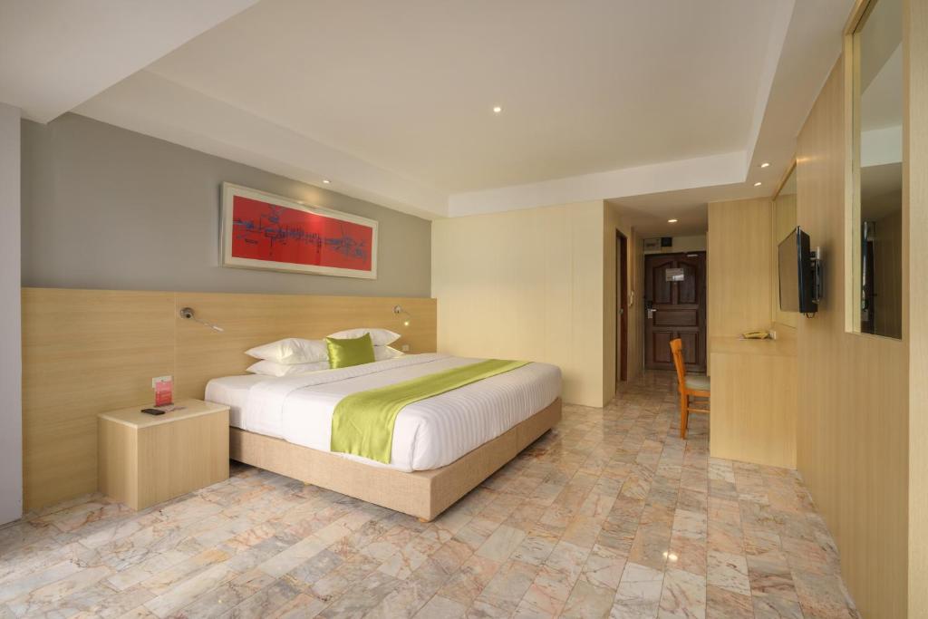 A spacious-looking double room has a large bed, wall-mounted television and small desk.