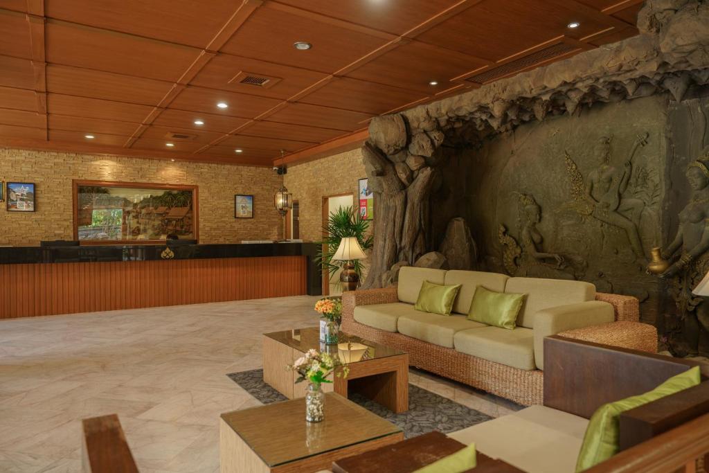 A warmly lit lobby combines a reception desk with a lounge framed by a dramatic rock relief.