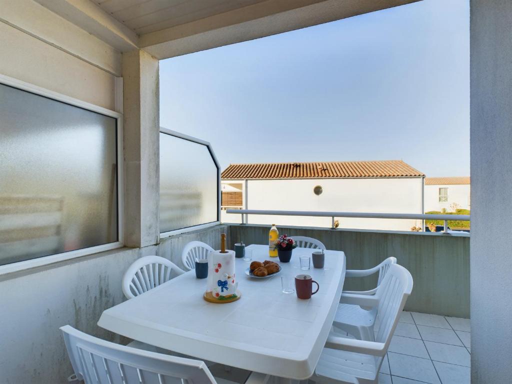 une table blanche et des chaises sur un balcon dans l'établissement Appartement pour 4 personnes aux Sables d'Olonnes, à Les Sables-dʼOlonne