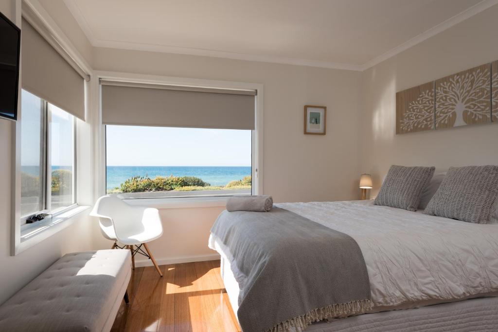 a bedroom with a large bed and a large window at Penguin Beach House in Penguin