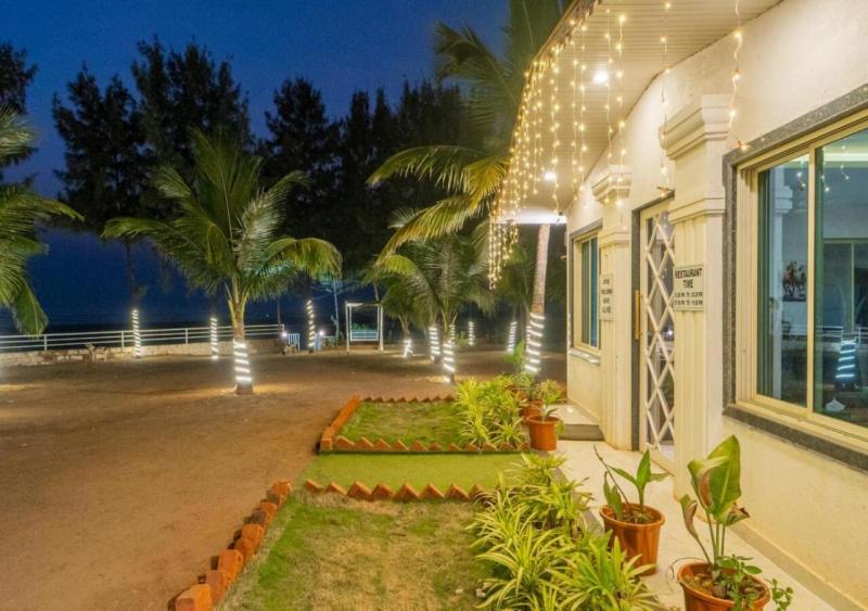 a building with palm trees and lights on it at Salt Water Resort in Dapoli