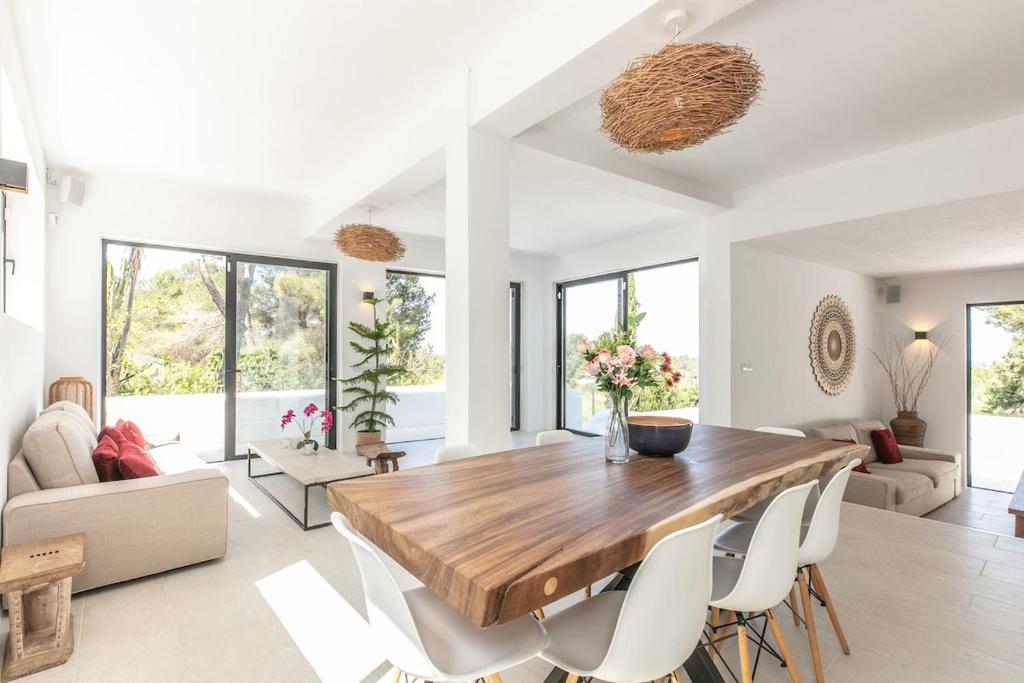 a living room with a wooden table and chairs at Sunset villa with pool and seaview in Cala Tarida
