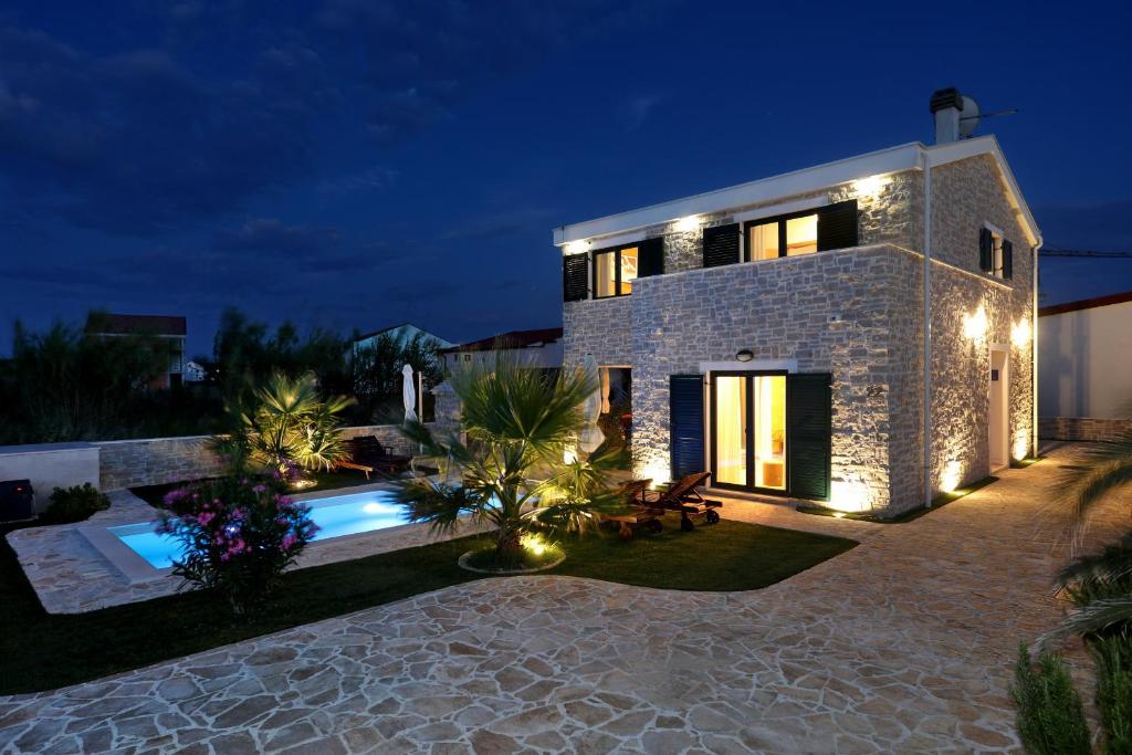 a villa with a swimming pool at night at Villa Stella with heated swimming pool in Privlaka