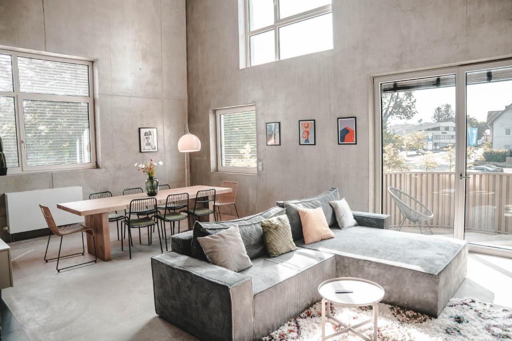 una sala de estar con un sofá y una mesa en Sunset Club - LOFT - 155 m2 Sichtbeton - Zentral, en Memmingen