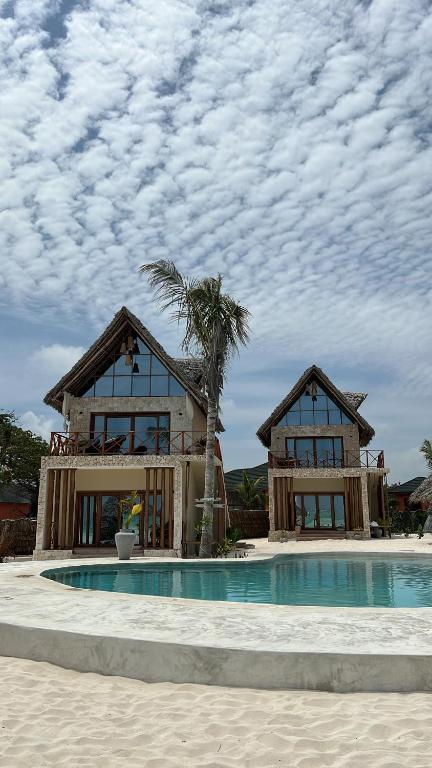 ein Haus mit einer Palme neben einem Pool in der Unterkunft Zanzi Soul Luxury Boutique Hotel in Jambiani