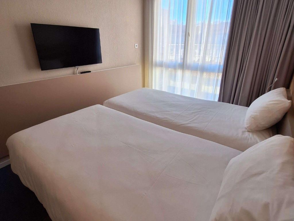 a hotel room with two beds and a flat screen tv at ibis Styles Toulon Centre Port in Toulon