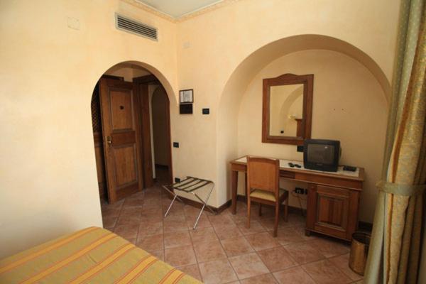 una camera da letto con scrivania, letto e specchio di Hotel Belvedere a Lanusei