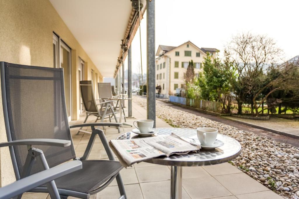 stół i krzesła na patio z 2 filiżankami kawy w obiekcie Anstatthotel Luzern - self-check-in w Lucernie