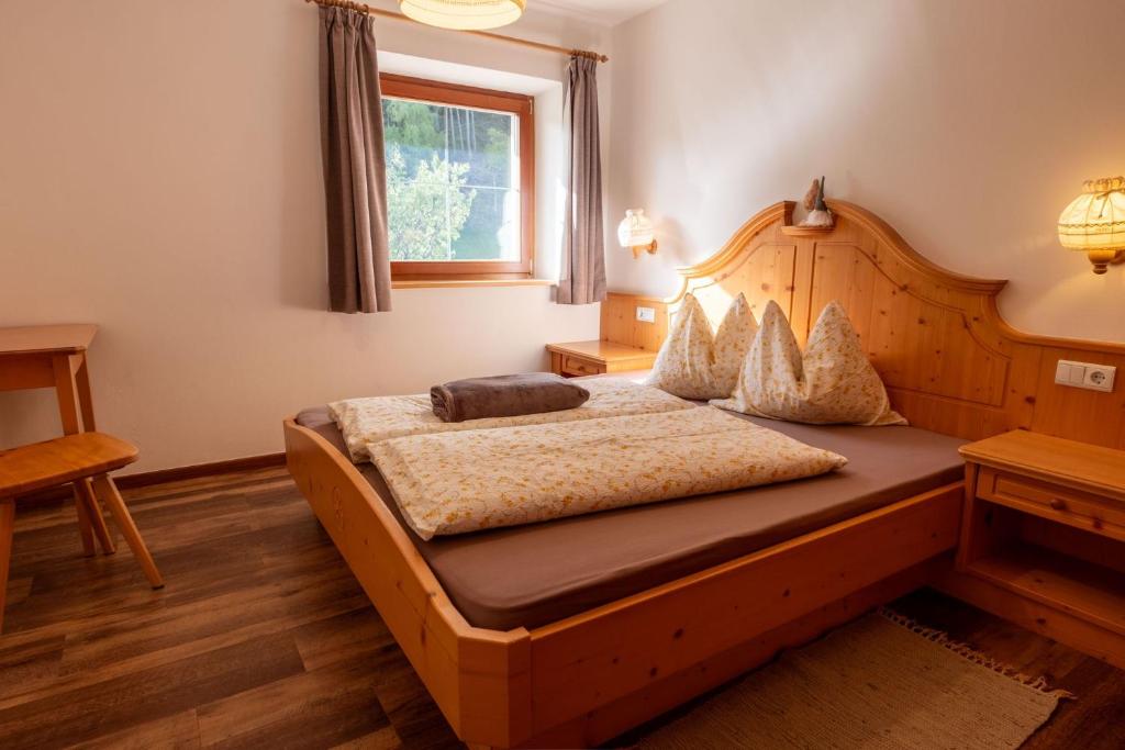 sypialnia z drewnianym łóżkiem i oknem w obiekcie Planitzhof w mieście Castelrotto