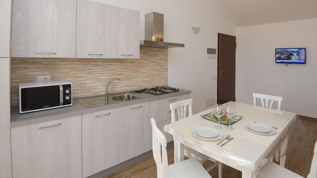 a white kitchen with a table and a microwave at Welcomely - Villa Paola B in Costa Rei