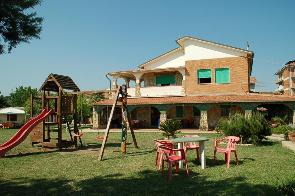 un parque infantil con mesa y sillas y una casa en Villaggio Rossi, en Porto Potenza Picena