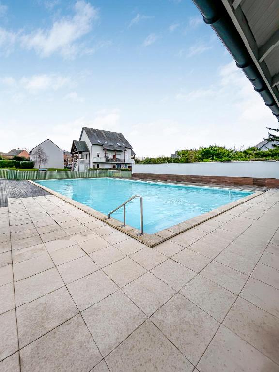une piscine vide avec une maison en arrière-plan dans l'établissement Les Cottages Honfleur, à La Rivière-Saint-Sauveur