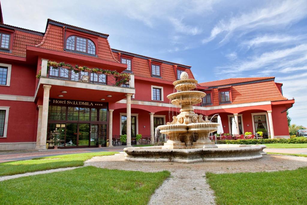 a fountain in front of a red building at Hotel sv. Ludmila in Skalica