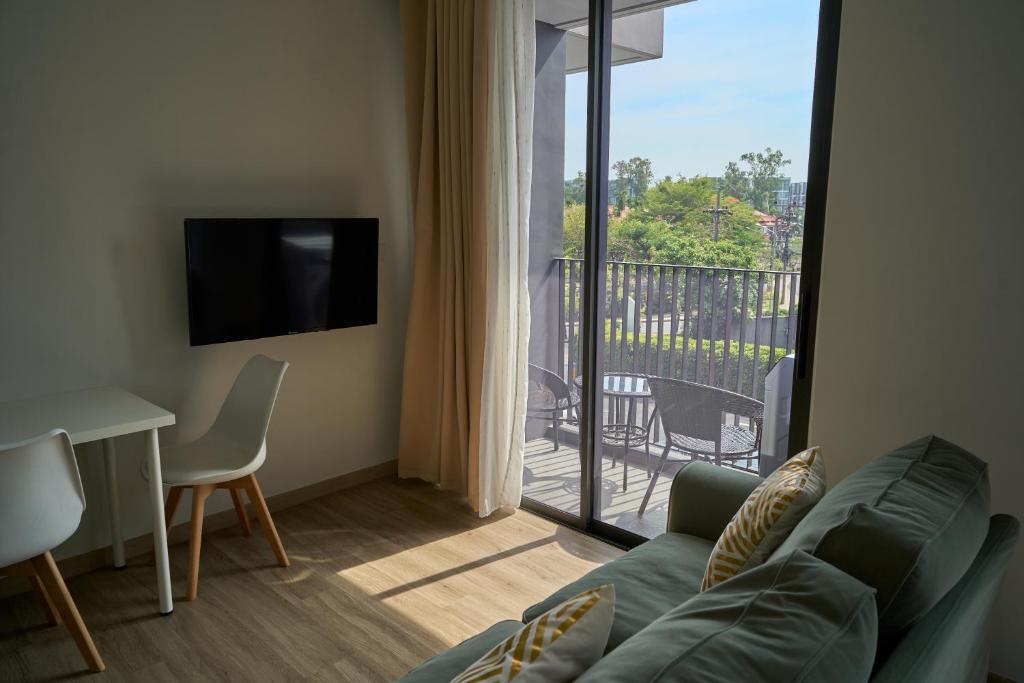 a living room with a couch and a view of a balcony at Cozy 1-bedroom Apartments in Laguna Skypark Bang Tao in Phuket Town