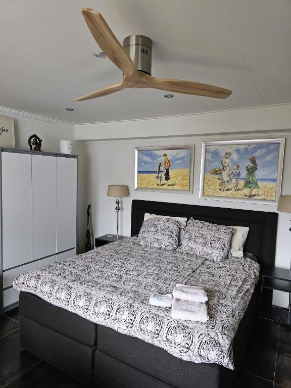 a bedroom with a bed with a ceiling fan at NamaStee aan Zee in Vlissingen