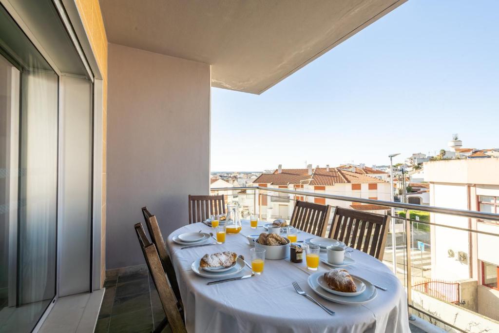 uma mesa com pratos de comida numa varanda em Sunset T3 - by Smarthomes em São Martinho do Porto