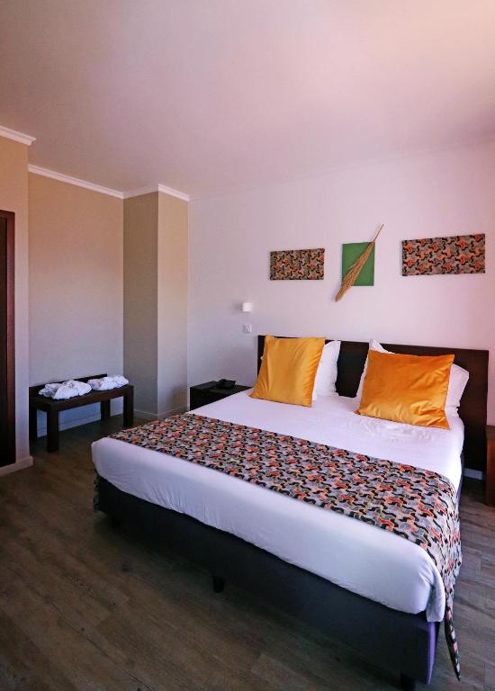 a bedroom with a large bed with orange pillows at Hotel Euro Moniz in Porto Moniz