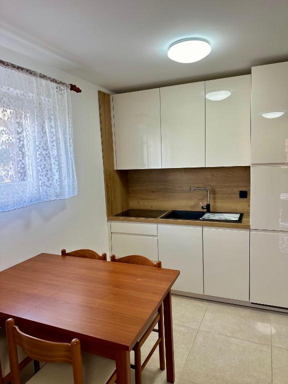 a kitchen with white cabinets and a wooden table at Litus in Njivice