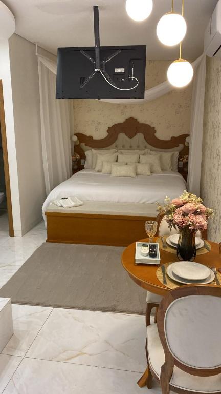 a bedroom with a large bed and a table with a table sidx sidx at Hotel Pousada Chalé das Flores in Sertãozinho
