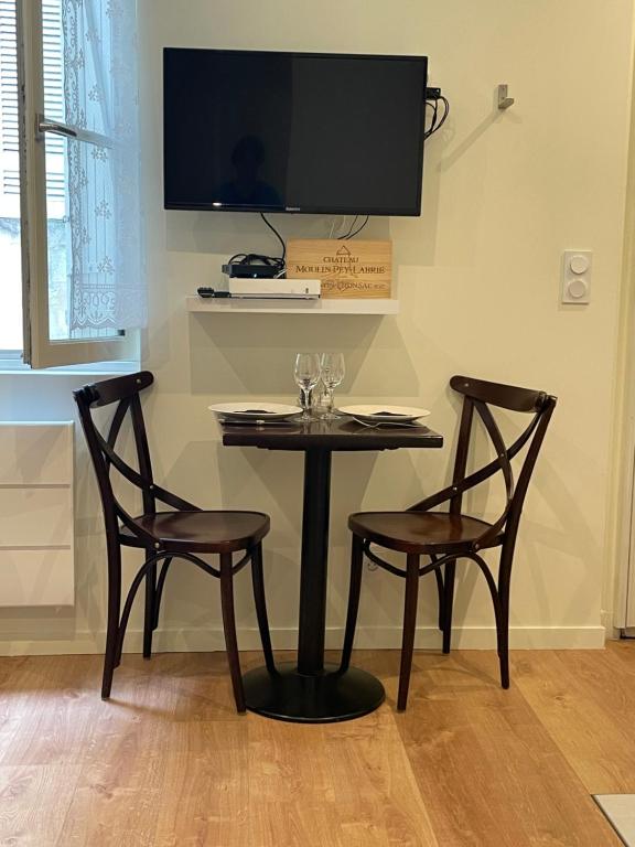 d'une table avec deux chaises et d'une télévision murale. dans l'établissement Bouquiere Studio, à Bordeaux