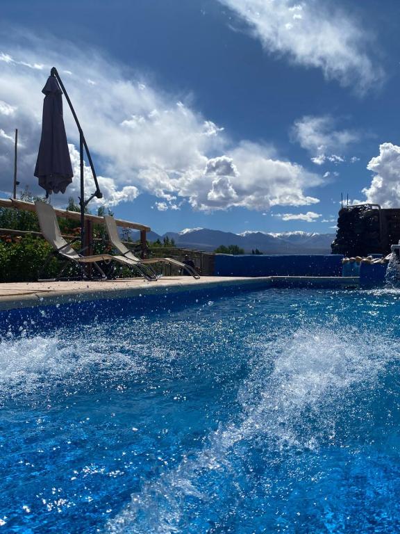an empty swimming pool with an umbrella and water at Complejo HUNUC in Barreal