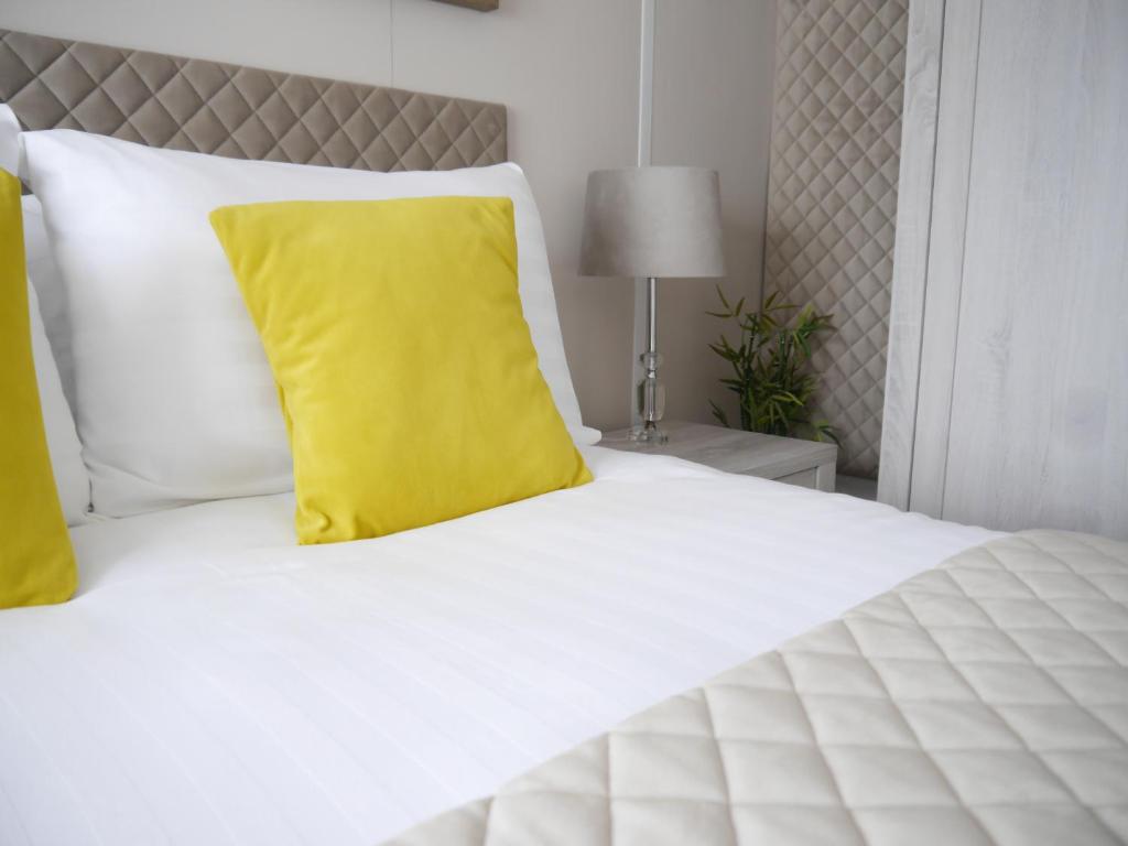 een wit bed met een geel kussen erop bij 101 Sapphire Tees Bay in Redcar