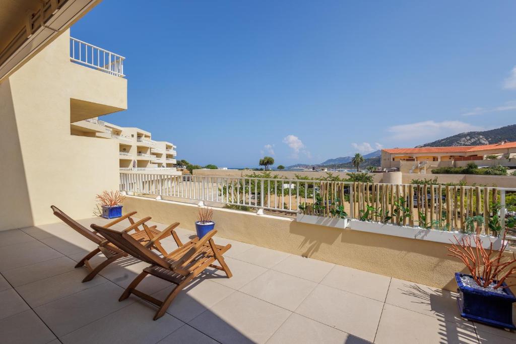 d'une terrasse avec 2 chaises et d'un balcon. dans l'établissement Le Palmier - Plage à 5 min vue mer et montagne, à Lumio