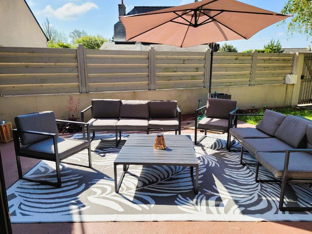 un patio avec des chaises, une table et un parasol dans l'établissement Villa Ker Sanmamaleo près de la plage - 4 chambres, 3 salles de bain, Wifi, animaux acceptés - FR-1-542-29, à Pleumeur-Bodou