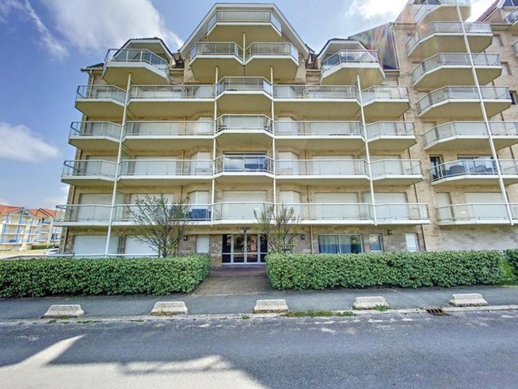 un grand bâtiment jaune avec des buissons devant lui dans l'établissement Appartement pour 4 pers. avec parking à Stella Plage - FR-1-236-156, à Cucq