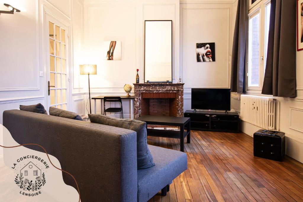 a living room with a couch and a tv at Ohana, appartement de charme, au centre de Lens in Lens