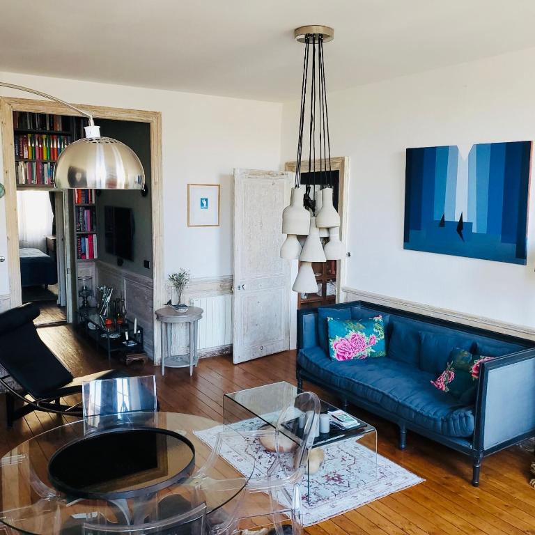 un salon avec un canapé bleu et une table en verre dans l'établissement The Appart 90m2 au coeur de la vieille ville, à La Rochelle