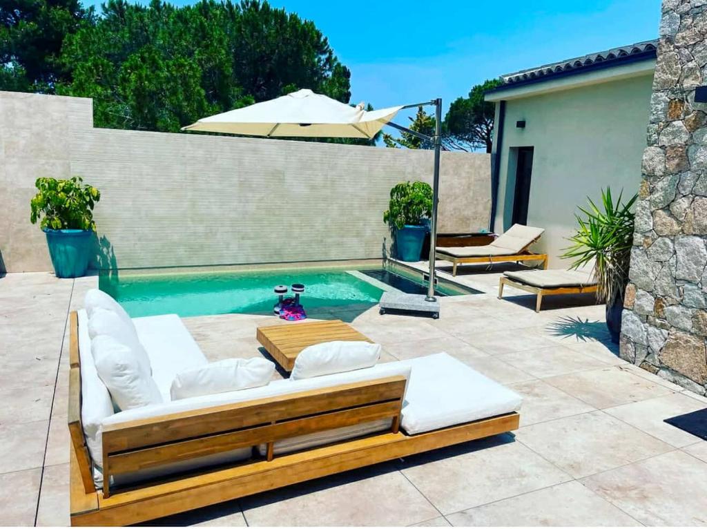 a backyard with a pool with a couch and an umbrella at Sublime villa vue mer pieds dans l'eau in Monticello